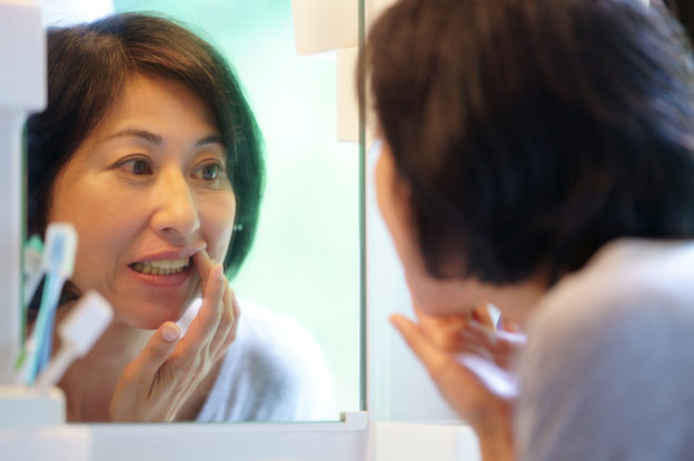 自分の歯を鏡で見ている女性