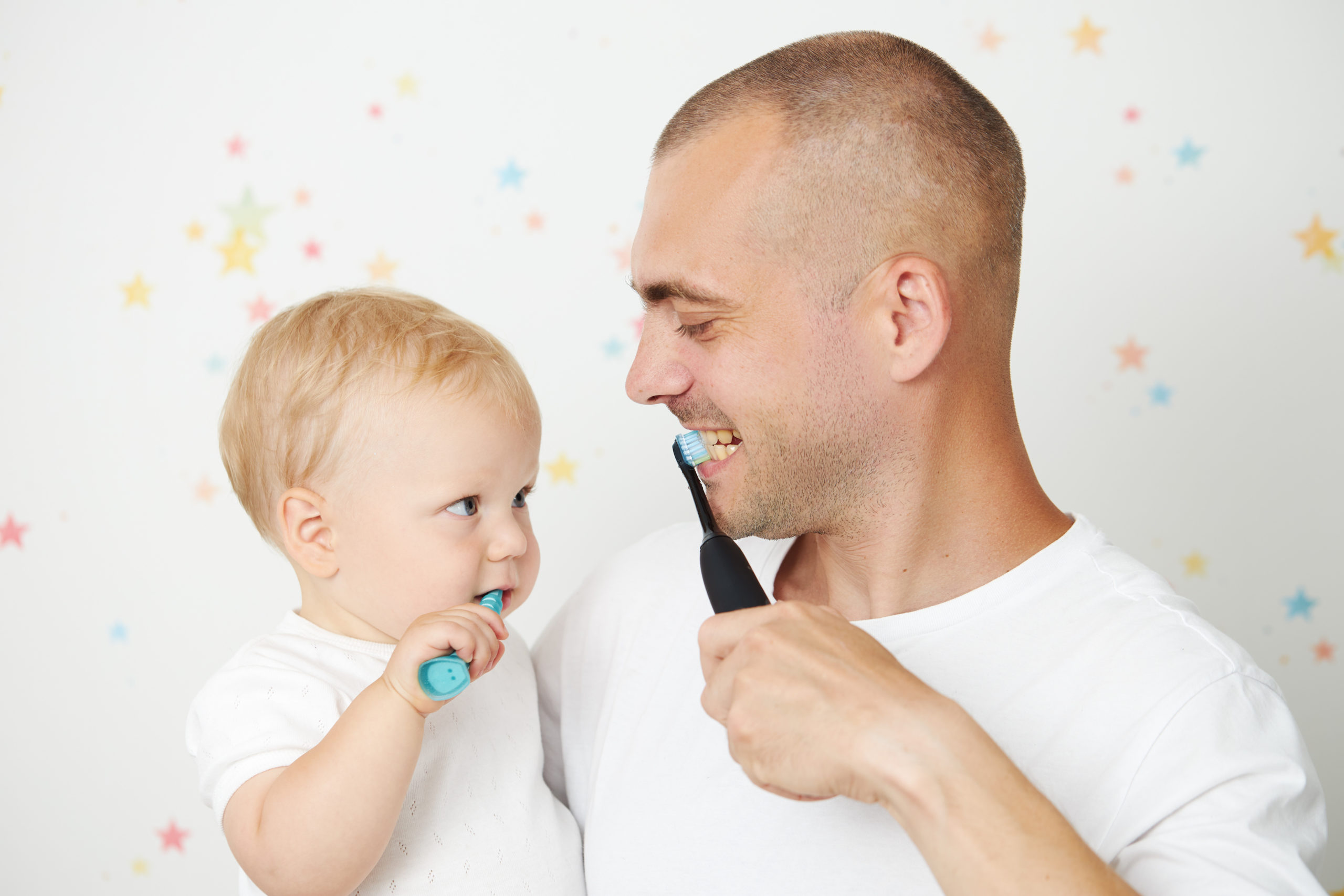 赤ちゃんを抱っこして歯磨きの仕方を教える父親