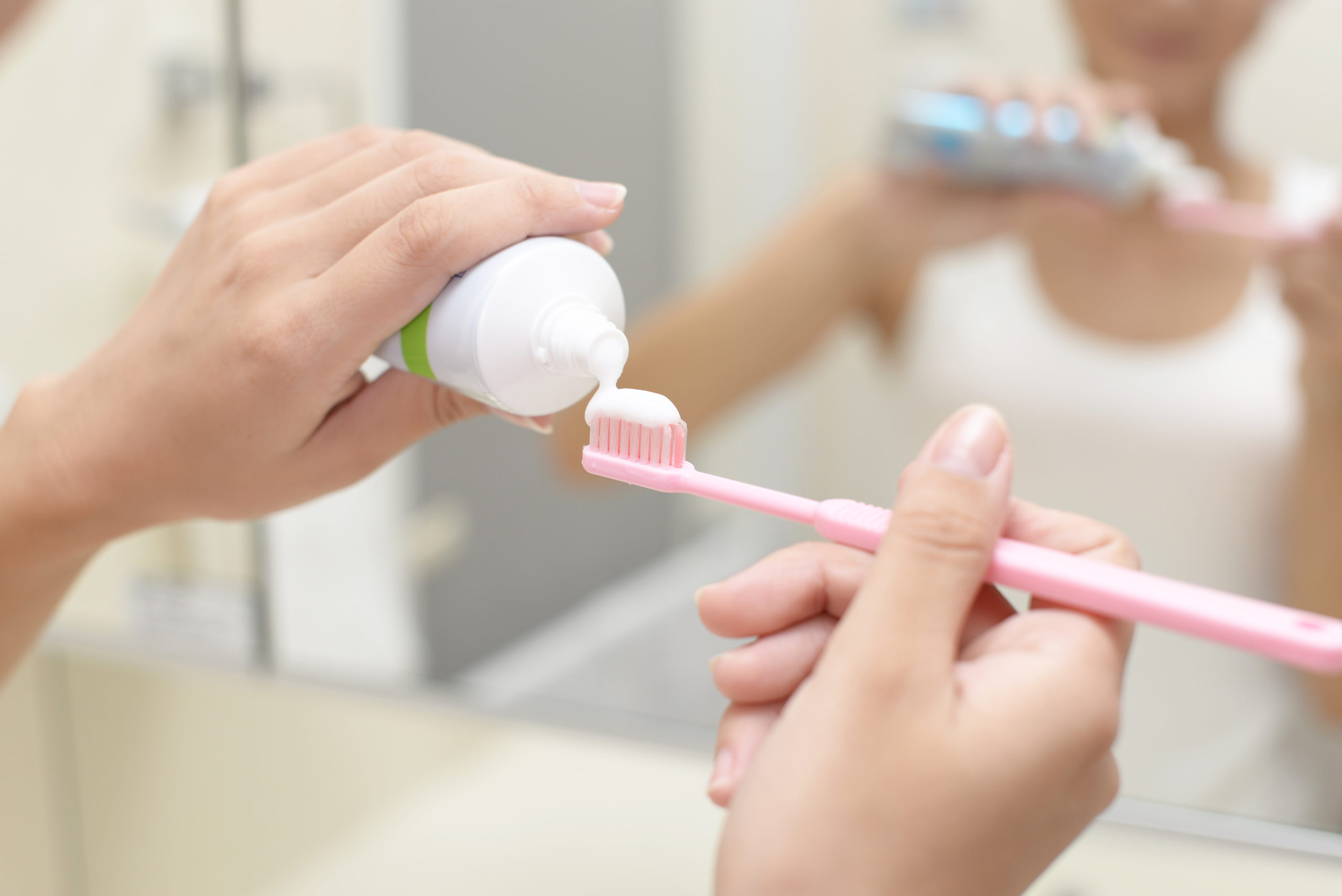 歯ブラシに歯磨き粉を絞る女性の手元