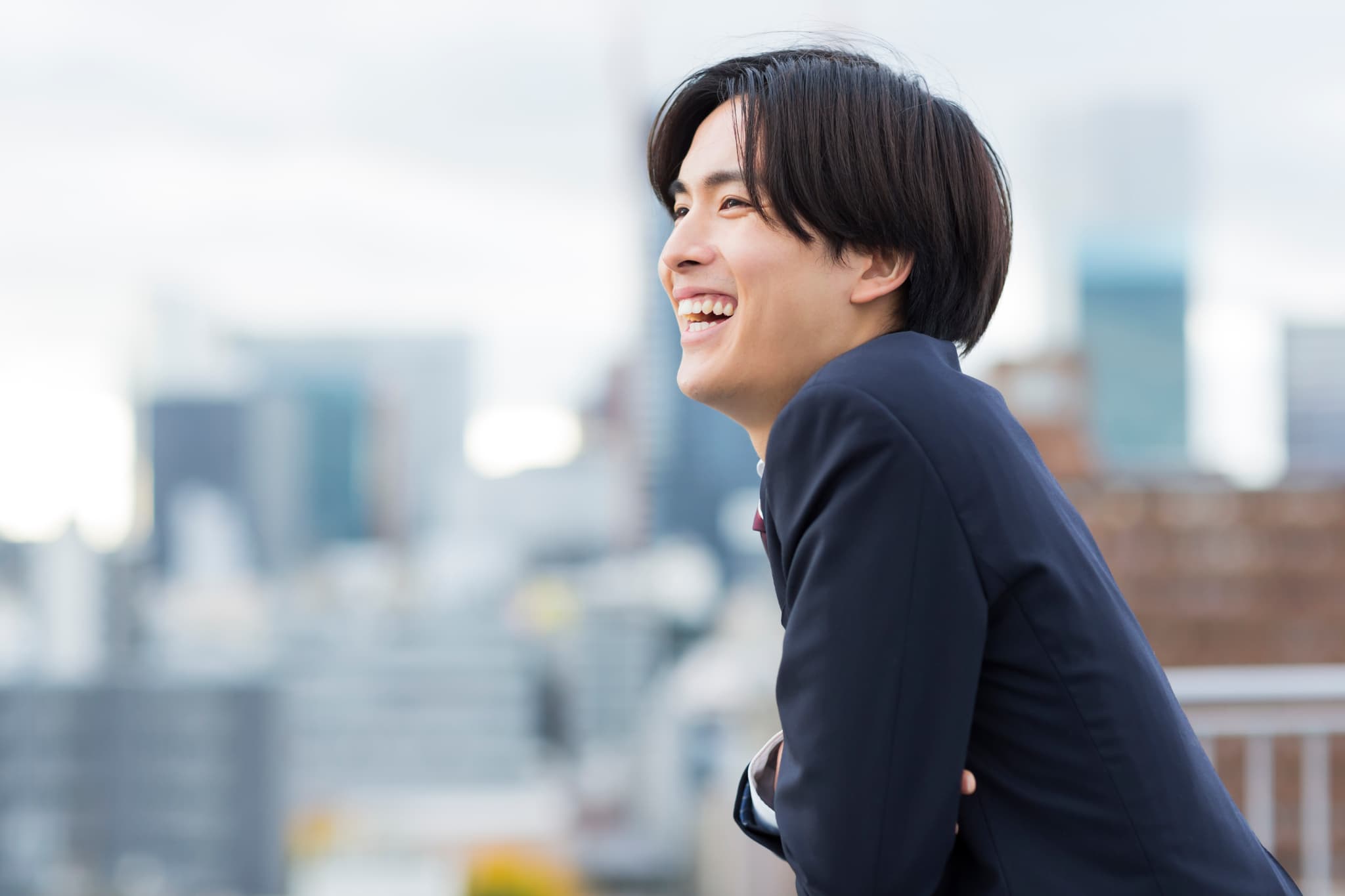 屋上で気持ちよさそうに微笑む男性