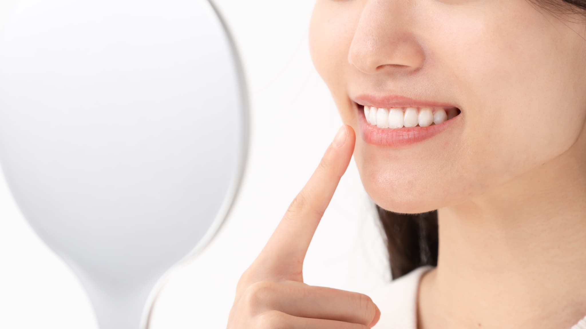 ホワイトニングした歯を鏡で見る女性