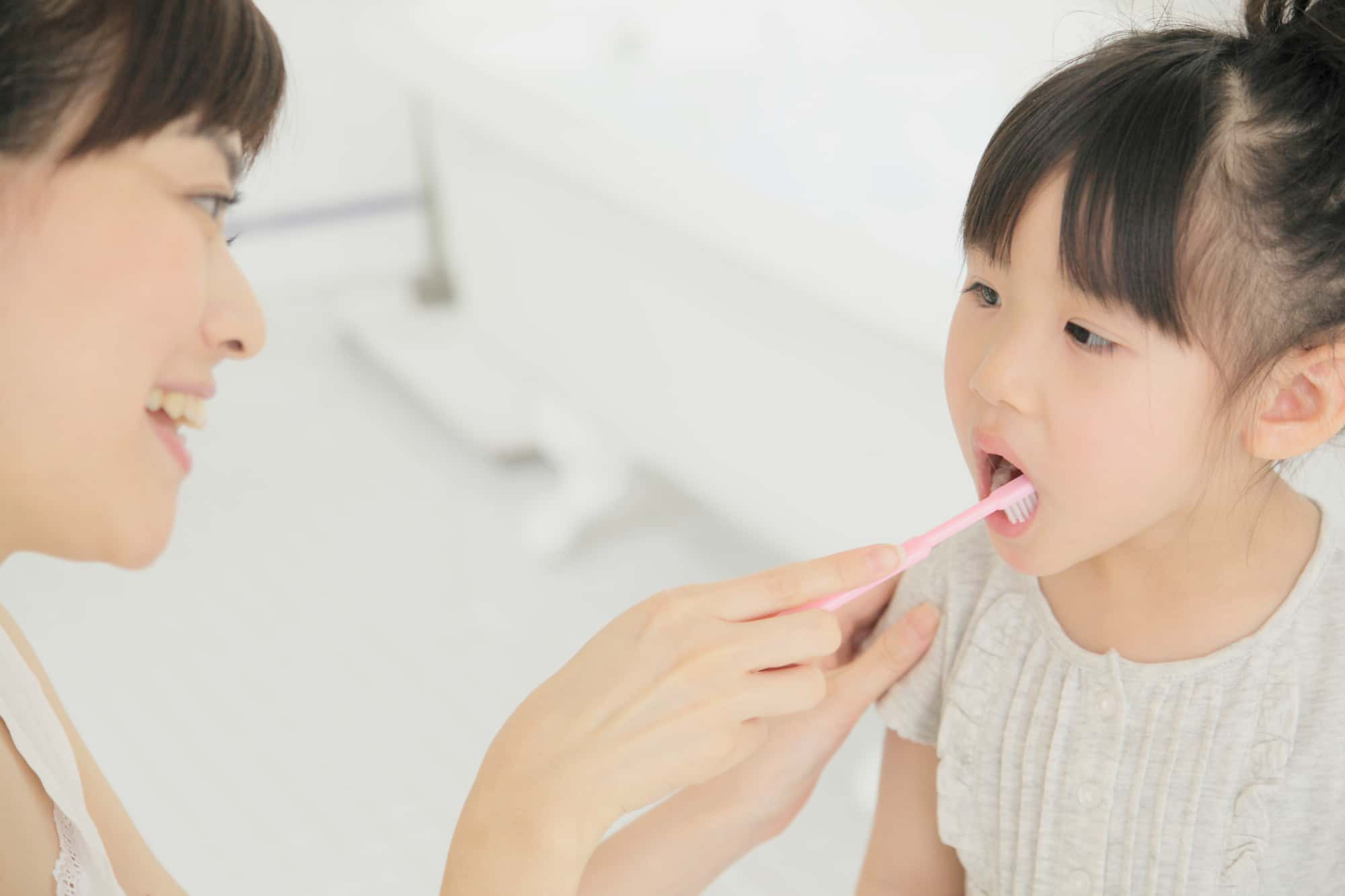 子どもに歯の仕上げみがきをしている母親